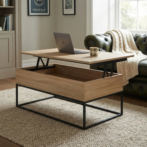 A lift-top coffee table with a light oak wood top and a matching storage drawer beneath, supported by a black metal frame. The table is shown in a living room setting with a laptop and mug on top, next to a green tufted sofa.