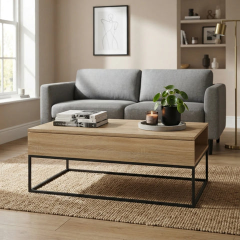 A modern coffee table with a light oak wood top and a black metal frame, styled in a living room setting with a gray sofa, a potted plant, and books on top.