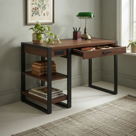 A wooden writing desk with a dark metal frame and open side shelves, shown in a styled home office setting with a plant, lamp, books, and window.